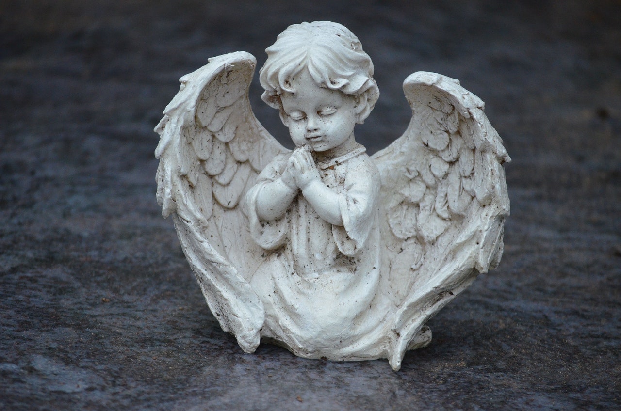 White Angel Figurine kneeling on the ground