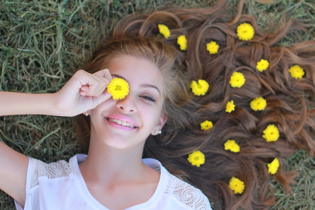 Woman Lying on Grass and Holding Yellow Flower