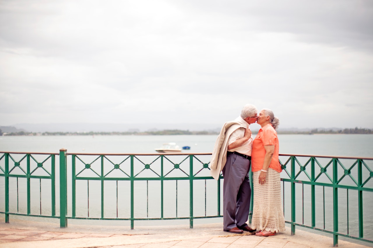 Stylish elderly couple kissing on embankment
