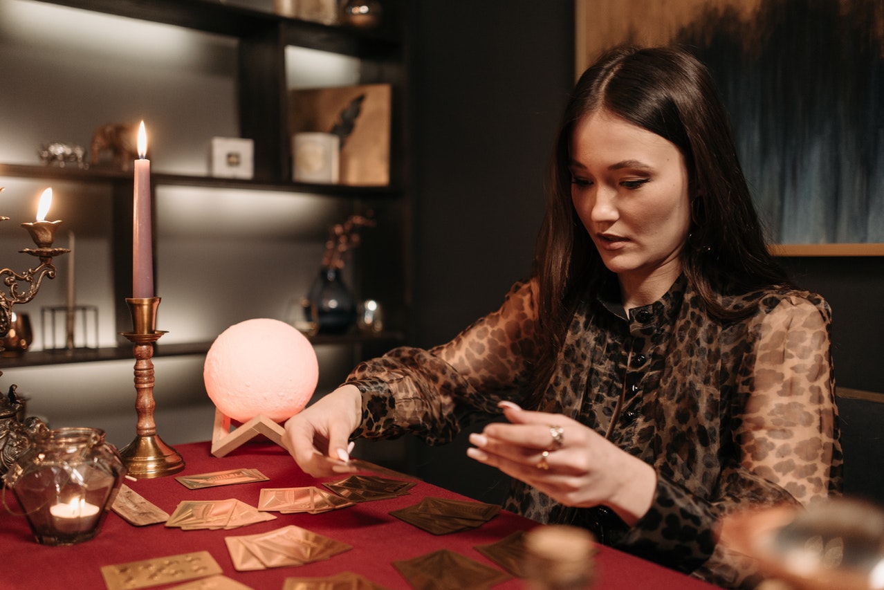 A Woman Holding Tarot Cards In A Dim Room