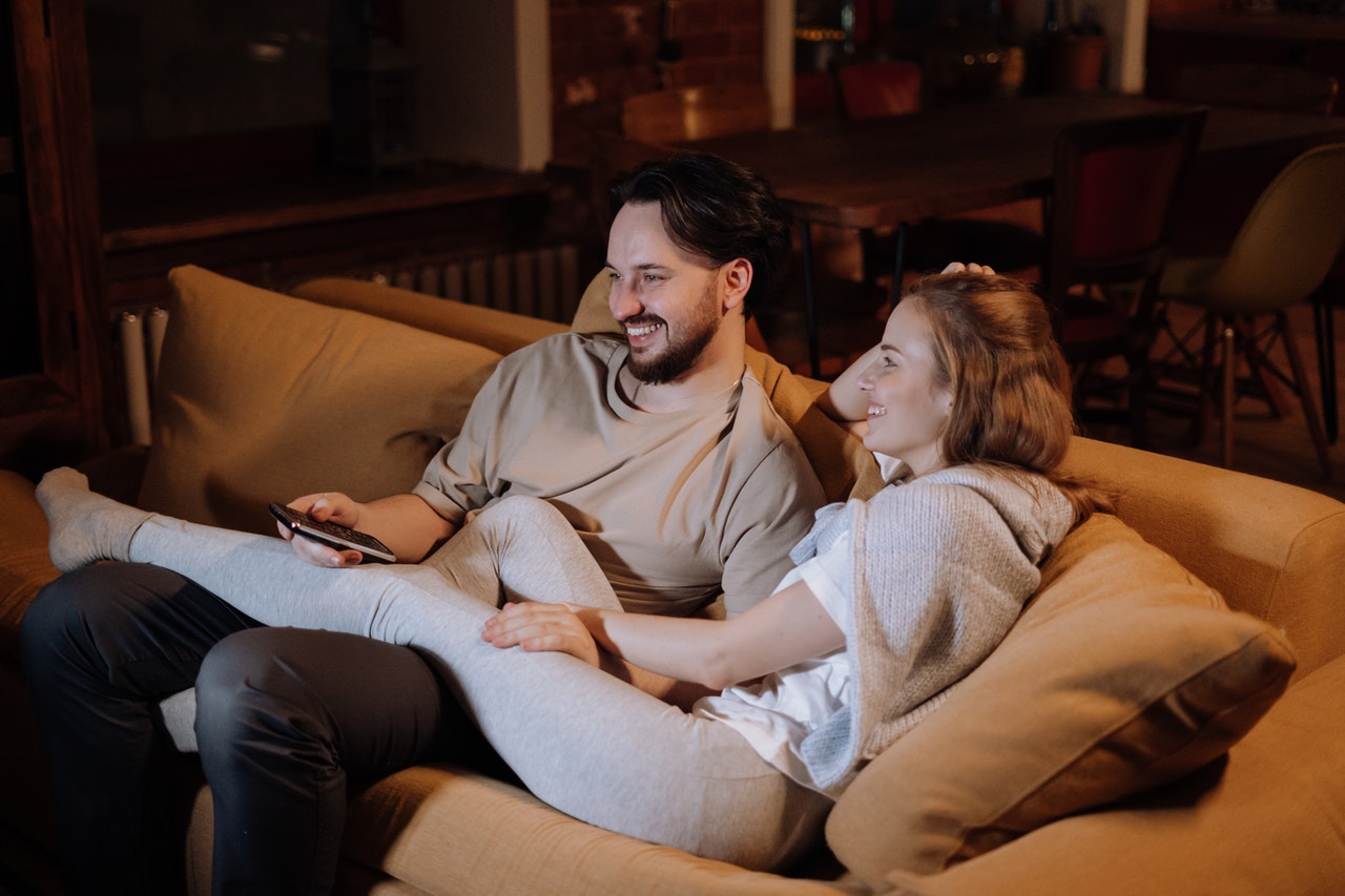 A Man and a Woman Sitting on a Couch While Watching TV