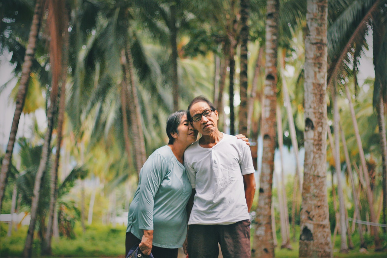 Old Couple Standing Together With Trees in the Background