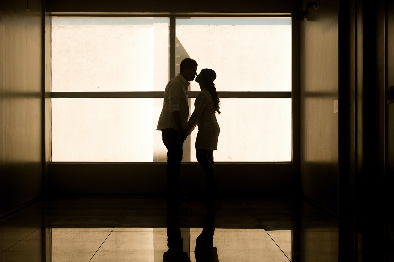 A Man and a Woman Holding Hands Near the Glass Window