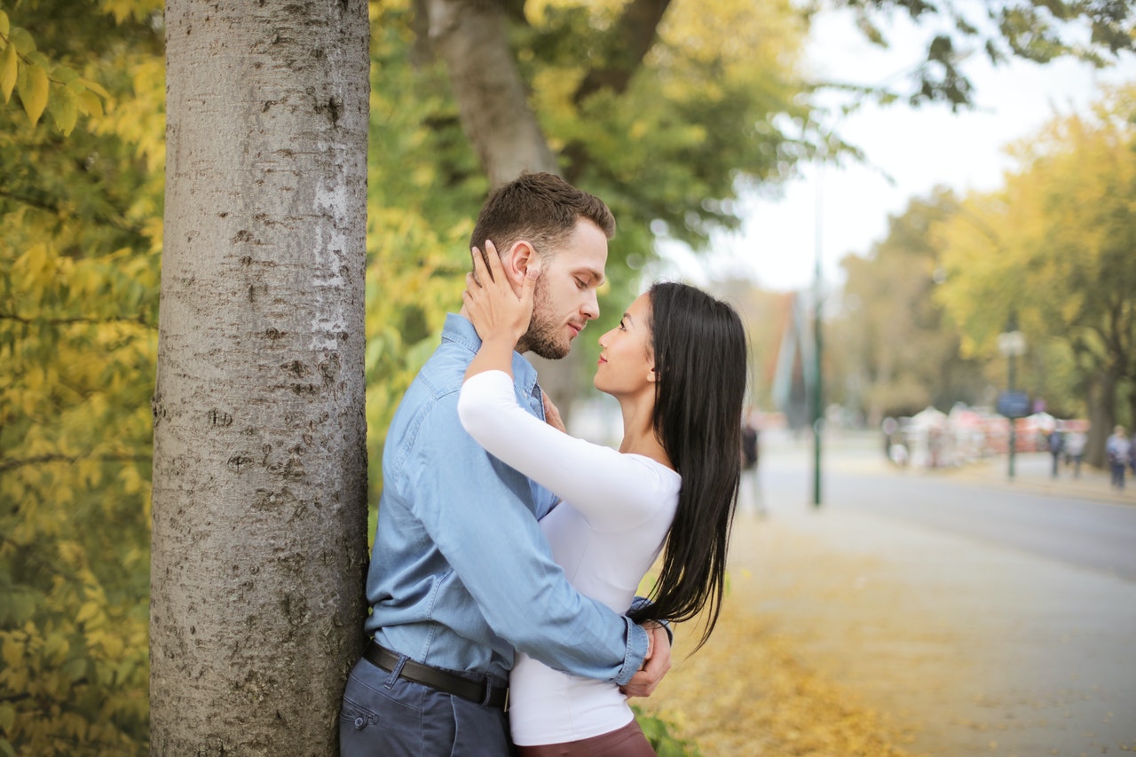Selective Focus of Hugging Couple Looking at Each Other While Standing Next to a Tree