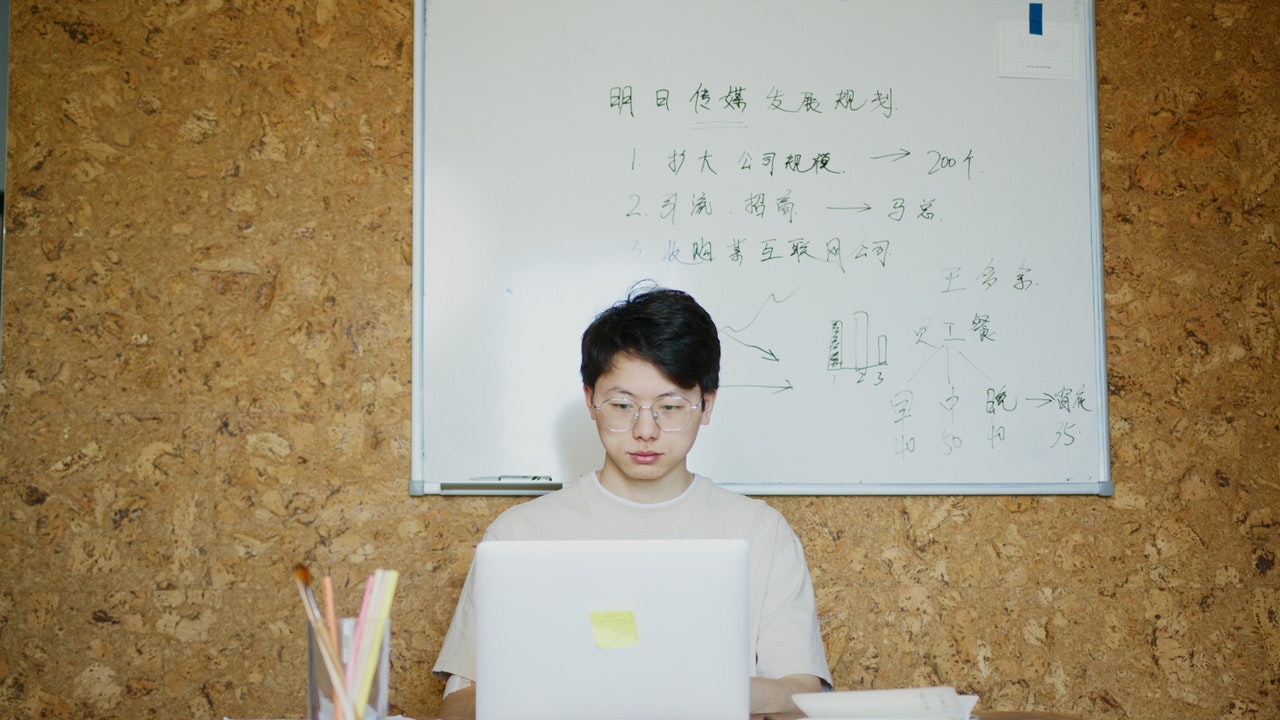 Man Using a Laptop in Front of a Whiteboard