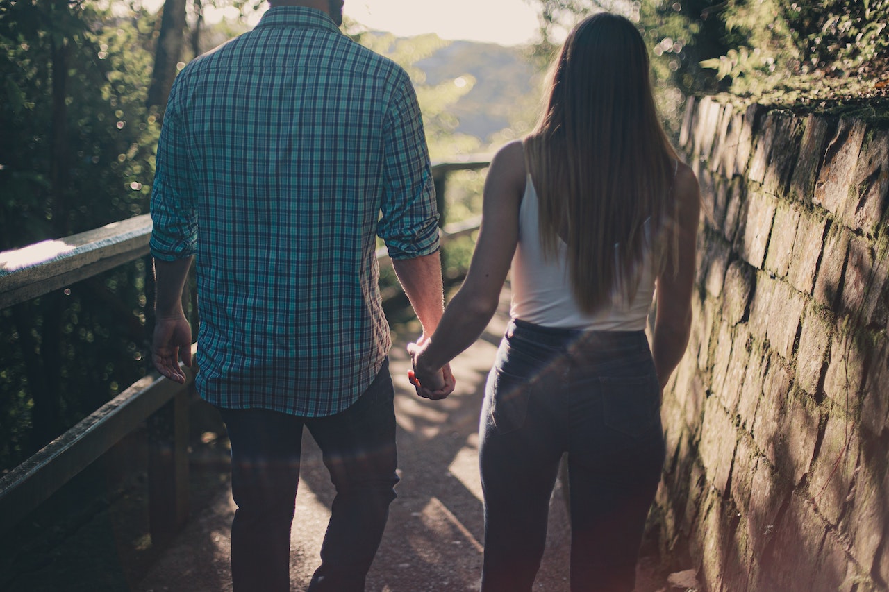 Couple Holding Hands While Walking Along Pathway