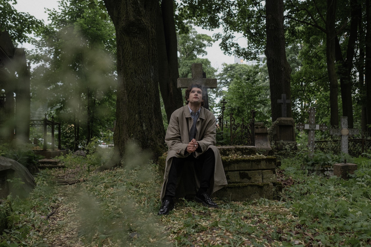 Man Smoking a Cigarette while Sitting on a Grave