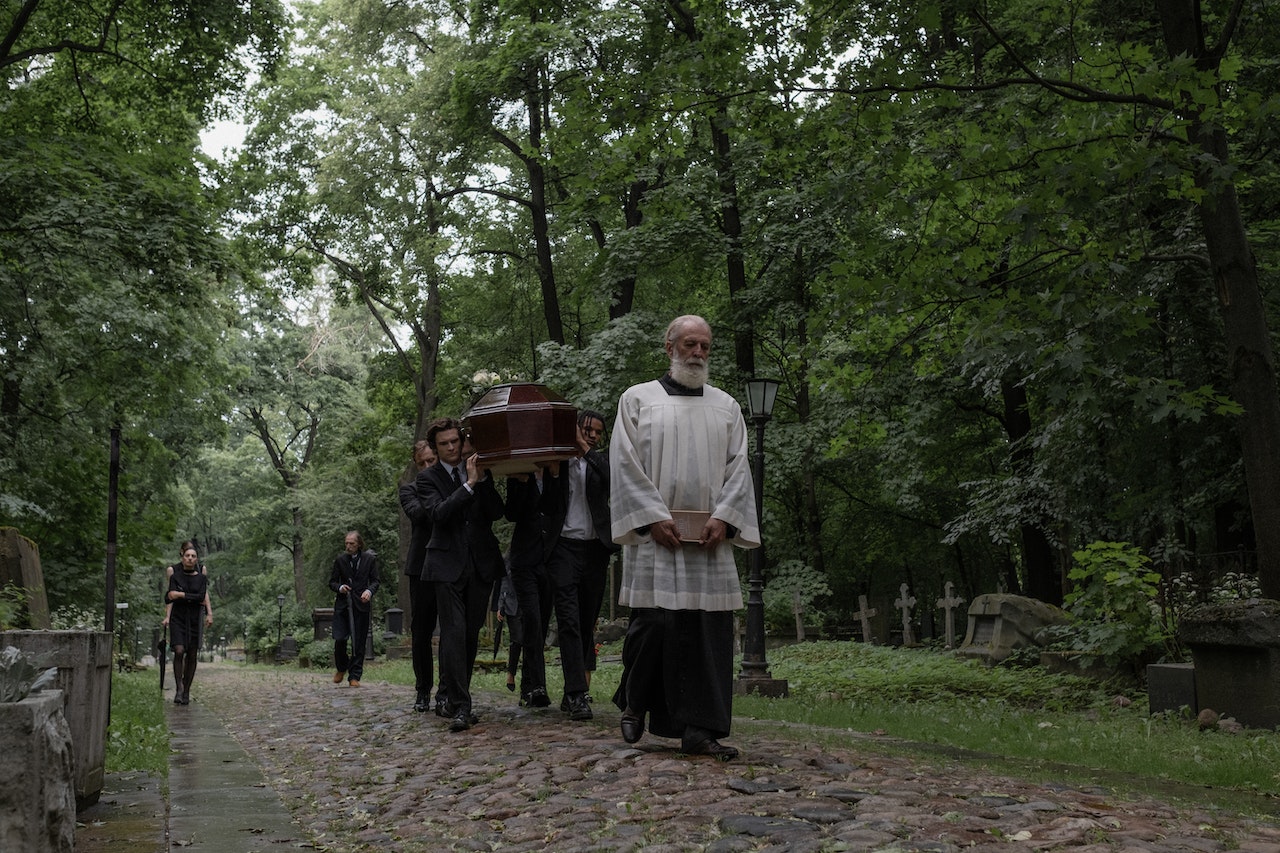 Men in Black Clothes Carrying a Coffin in Cemetery